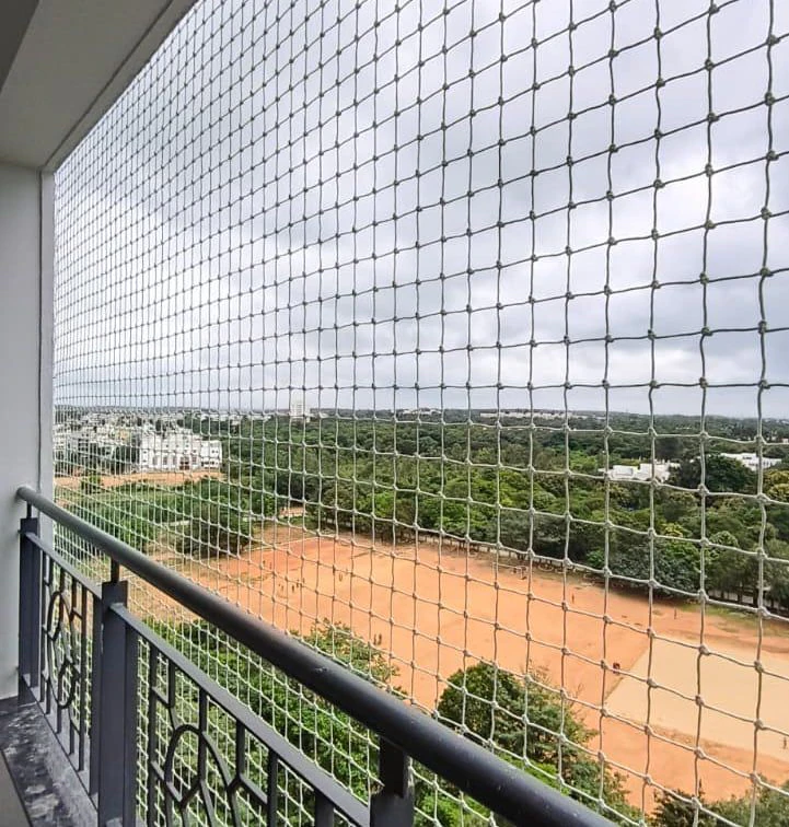 Balcony safety net stretched across an apartment balcony overlooking open land