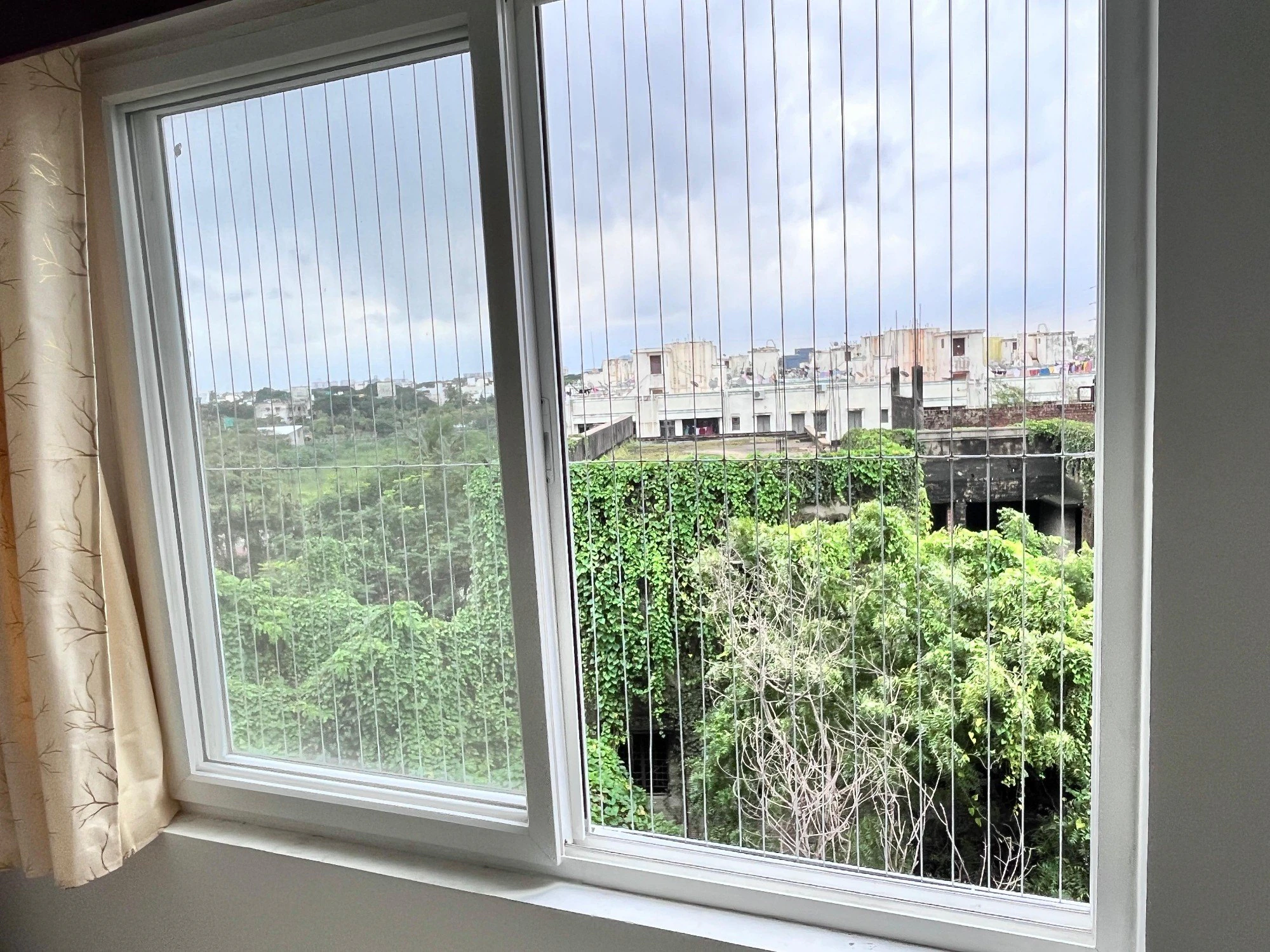 Bedroom window fitted with invisible grills, the green view outside unbroken
